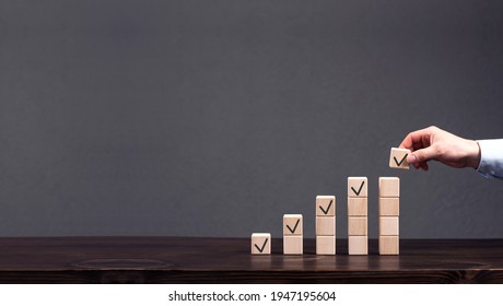 Wooden cubes are stacked in ascending order. The businessman's hand puts the top cube. Profit, finance growth concept. Progress - Shutterstock ID 1947195604