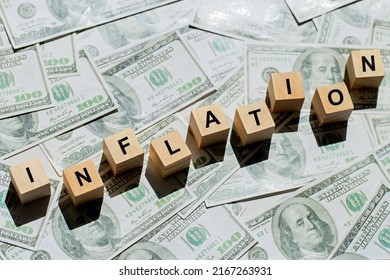 Wooden Cubes With Text Inflation On US Dollar Money Banknote. 
The Idea For FED Considers Interest Rate Hikes, World Economics, And Inflation Control, Concept Shows Rising Inflation.