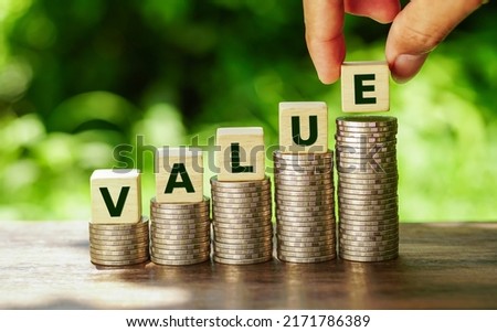 Wooden cubes with value word on stacked of coins in stair shape on nature background.             