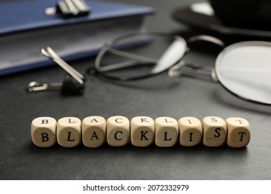 Wooden Cubes With Word Blacklist And Office Stationery On Black Desk, Closeup