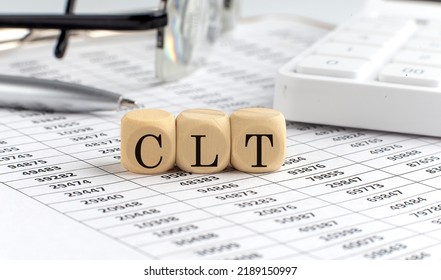 Wooden Cubes With The Word Central Limit Theorem -CLT On A Financial Background With Chart, Calculator, Pen And Glasses, Business