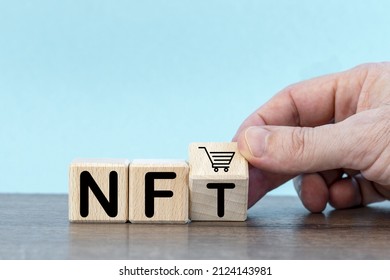 Wooden cubes with word NFT. hand, trolley.buying and sale type of cryptographic nft tokens. Future of art NFT market. Cryptocurrencies and e-commerce. Production and sale Non fungible token. 
