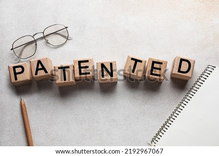 Wooden cubes with word PATENTED on light background