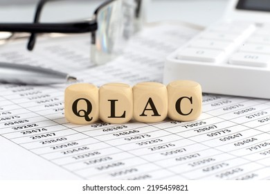 Wooden Cubes With The Word QLAC Qualified Longevity Annuity Contract On Financial Background With Chart, Calculator, Pen And Glasses, Business Concept.