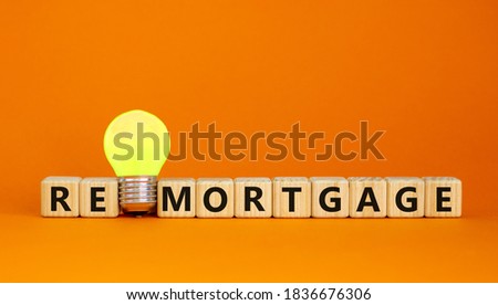 Wooden cubes with word 'remortgage'. Yellow light bulb. Beautiful orange background. Business concept. Copy space.