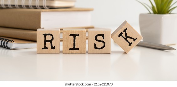 Wooden Cubes With The Word Risk. Risk Taking, Risk Management Or Assessment Concept. Eliminate Risk In Business Finance Decisions.