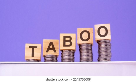 Wooden Cubes With The Word Taboo On Money Pile Of Coins, Business Concept, Purple Background