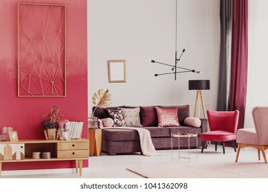 Wooden Cupboard Against Red Wall In Decorative Living Room Interior With Copper Table And Violet Sofa