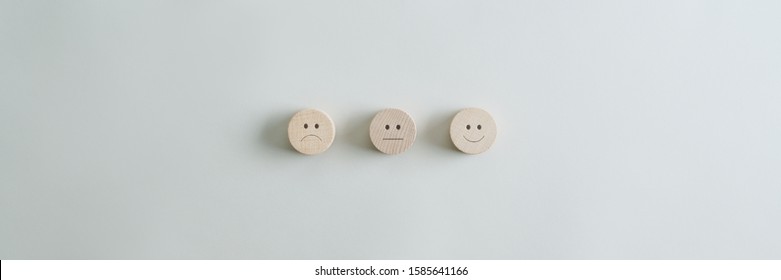 Wooden Cut Circles With Faces Representing Positive, Negative And Neutral Grade Placed In A Row Over Grey Background. Wide View Image With Copy Space.