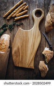 Wooden Cutting Board In The Form Of A Large Knife Or Ax Top View. Empty Wooden Cheese Plate Along With Bread And Baguette.