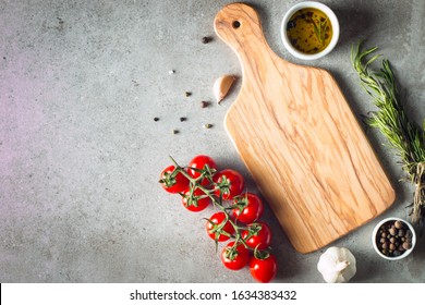 Wooden Cutting Board with Fresh Herbs and Raw Vegetables on Rustic Wood Table. Top view. Cooking background. 