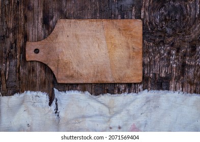 Wooden Cutting Board And Old Tattered Fabric On A Textured Wooden Background. Top View. Selected Background.