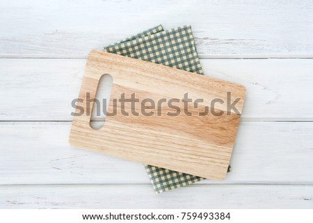 Wooden cutting board on napkin placed on white wooden table ,top view or overhead shot , food menu card or recipes background concept