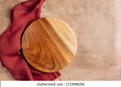 Wooden Cutting Board Over Towel On Beige Rustic Kitchen Table. Space For Your Recipe Or Menu. Top View.