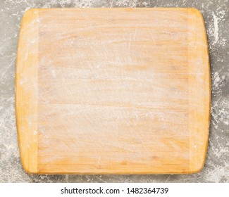 Wooden cutting board sprinkled with empty flour on a gray background. Copy space. Template for text or design. Top view