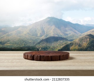 Wooden cuttingboard on wooden table for standing product against nature landscape