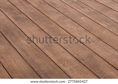 A wooden deck background, featuring a pattern of diagonal planks with visible wood grain and texture.