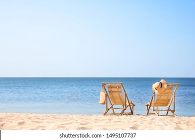 Wooden Deck Chairs On Sandy Beach Near Sea