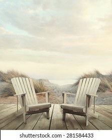 Wooden deck with chairs, sand dunes and ocean at sunset