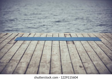 wooden deck near the lake and unrolled yoga mat on the floor - Powered by Shutterstock