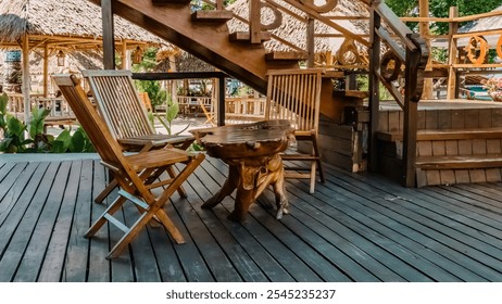 A wooden deck with a table and chairs. The chairs are wooden and the table is made of wood. The deck is outside and has a tropical feel - Powered by Shutterstock