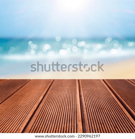 Wooden deck table top on blurred background of tropical beach and sea.
