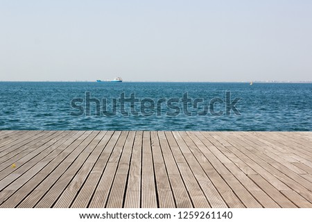 wooden deck waterfront sea shoreline background texture and water surface with small waves with horizon line, wallpaper pattern, copy space