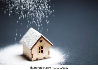 Wooden Decorative Toy House Standing In Winter Undedr Snow On Black Background. Purchasing Or Buying A House Or Rental Of Property, Cosy Home And New House For Children Concept