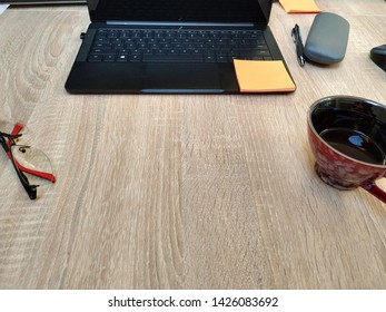 Wooden Desk With Laptop, Sticky Notes, Glasses, Coffee Cup And Pen Seem From First Person Perspective