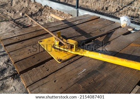 Wooden desk with steel rod bending machine at construction site. The armature bending machine closeup view