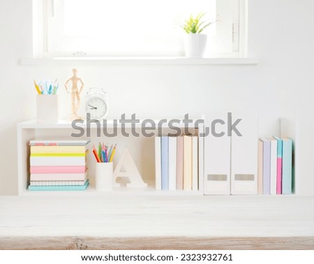 Wooden desk top on blurred bookshelf with school supplies background