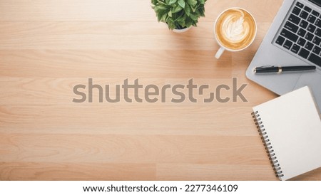 Wooden desk workplace with laptop computer, notebook, pen and cup of coffee, Top view flat lay with copy space.