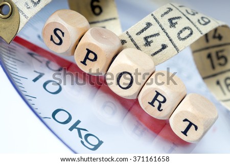 Wooden dice with the word sport and tape measure with a body scales / Sport