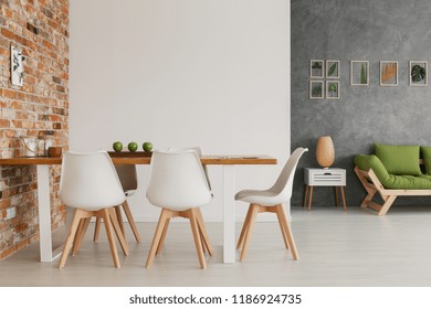 Wooden Dining Table And Chairs By An Exposed Brick Wall In A Bright And Natural Living Room Interior Of A Modern Loft