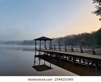 Wooden dock at calm, mist-covered lake during an early morning - Powered by Shutterstock