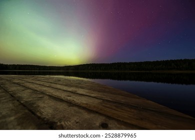 A wooden dock extending into a calm lake under a stunning aurora, with shades of green and purple in the night sky, reflecting off the still water, creating a peaceful and picturesque scene. - Powered by Shutterstock