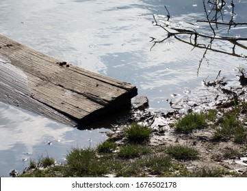 A Wooden Dock Half Underwater On The Shore Of A Lake.