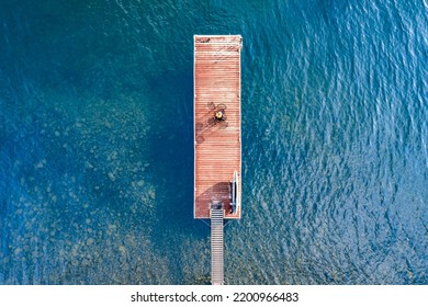 Wooden Dock On A Clear Blue Water Lake On A Sunny Day Overhead Aerial