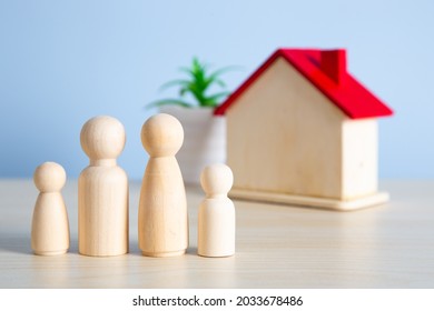 Wooden Doll Family Stands In Front Of House Model.