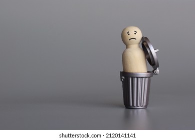 Wooden doll inside trash can. Down in the dumps, depressed, sad and miserable concept. Copy space