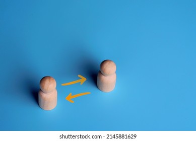 Wooden dolls and exchange arrow on blue background. Copy space. Share, network, peer to peer concept