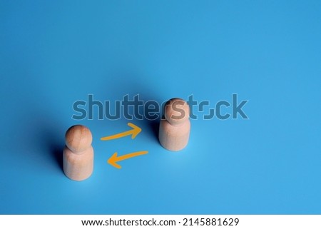 Wooden dolls and exchange arrow on blue background. Copy space. Share, network, peer to peer concept