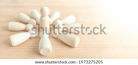 The wooden dolls are lined up on a wooden table with a white backdrop and one in the center, Stand out and ahead of its competitor. Concept of leader. Business competition planning teamwork strategy.
