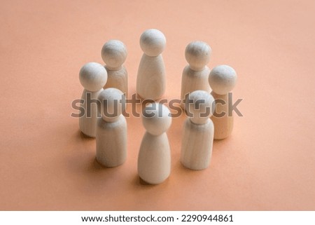 Wooden dolls standing in a circle facing each other. Team decision or working together concept.