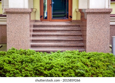 A Wooden Door With A Frame And Glass Inserts On The Facade Of A Building With A Threshold And A Granite Staircase And A Stone Plinth Close-up, Green Bushes At The Entrance.