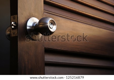 wooden door with grill, stainless door knob or handle on wooden door in beautiful lighting