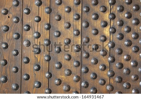 Wooden door of old castle, reinforced with metallic bolts.