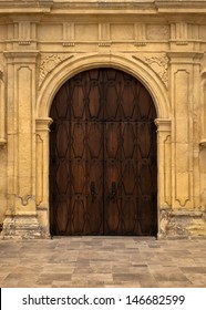 An Wooden Door Within Ornate Plaster Framing.