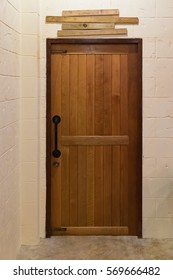 Wooden Door With Wood Nameplate On The Top With Wall In Dark Empty Room.