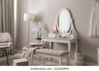Wooden dressing table with decorative elements and makeup products in room. Interior design